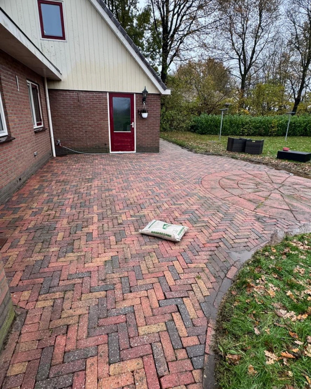 Oprit van rode en grijze klinkers in visgraatverband bij een woning