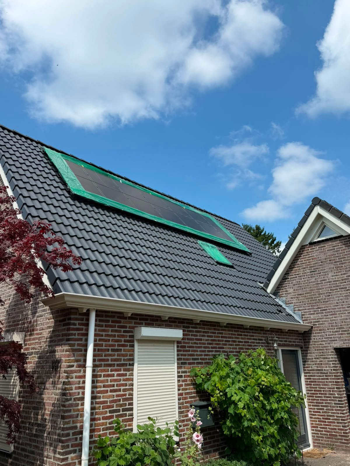 Betonpannendak na de coating, egaal donker, met de zonnepanelen nog afgeplakt met groene folie