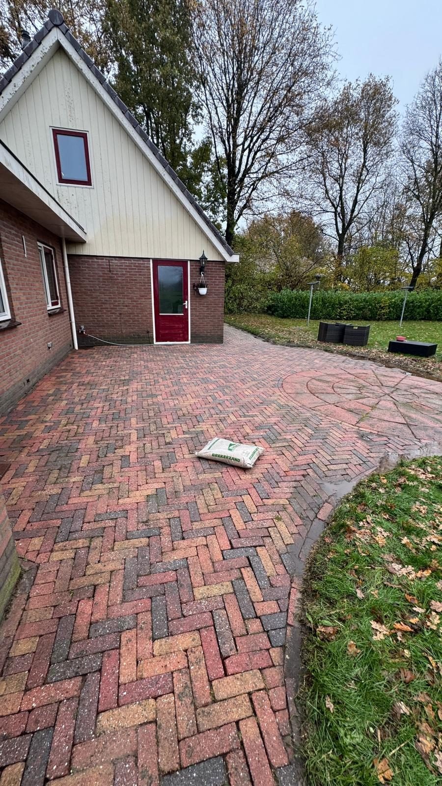 Na: hetzelfde terras vanaf de hoek van het huis, de klinkers weer rood en helder