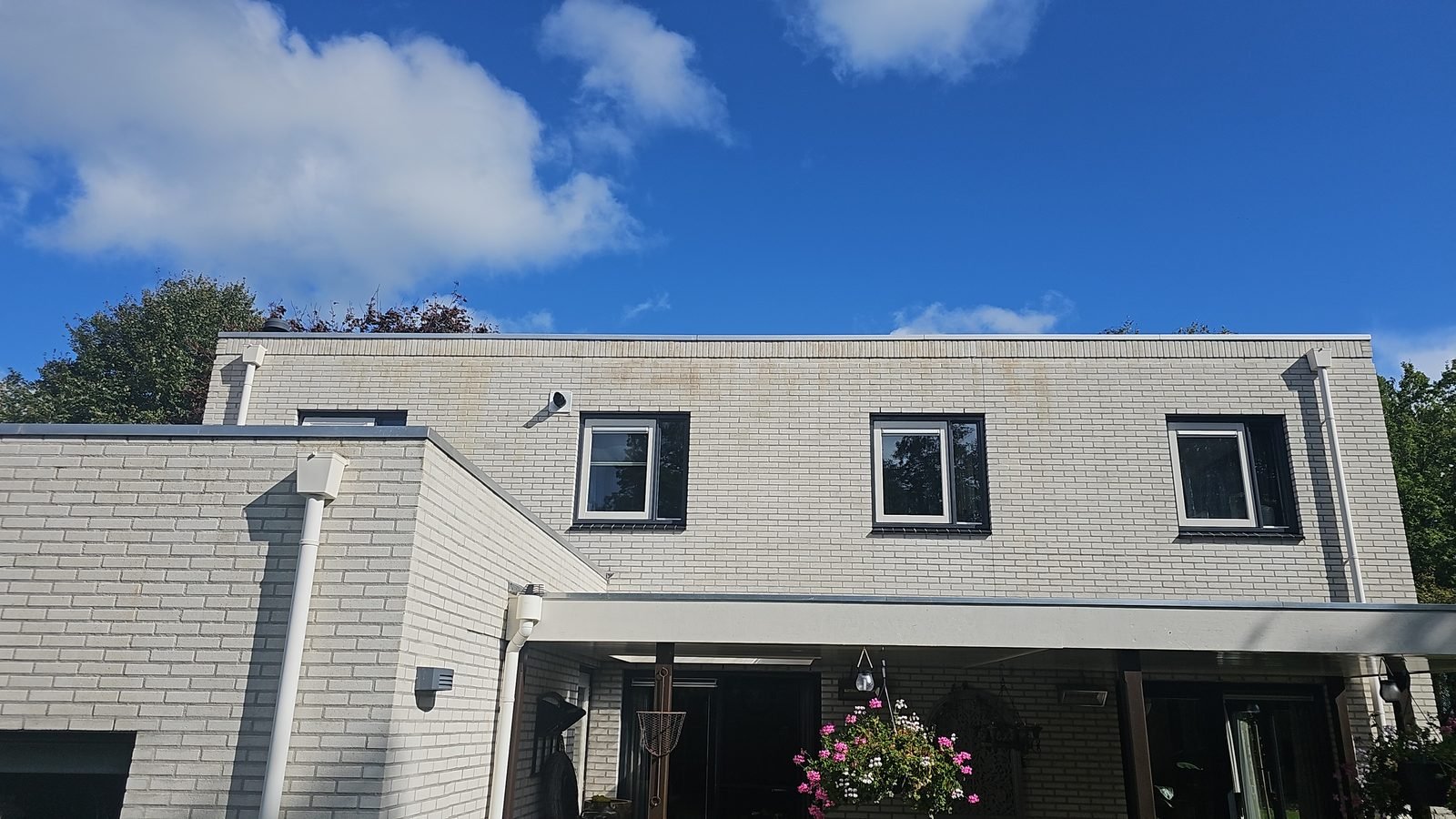 Na: dezelfde woning van iets verder weg, de gevel egaal wit