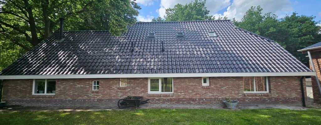Donker pannendak van een bungalow na de reiniging, boven een bakstenen woning