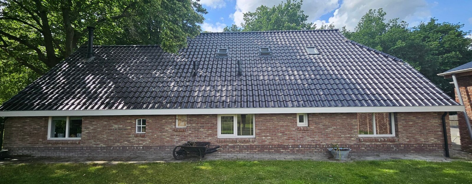 Donker pannendak van een bungalow na de reiniging, boven een bakstenen woning