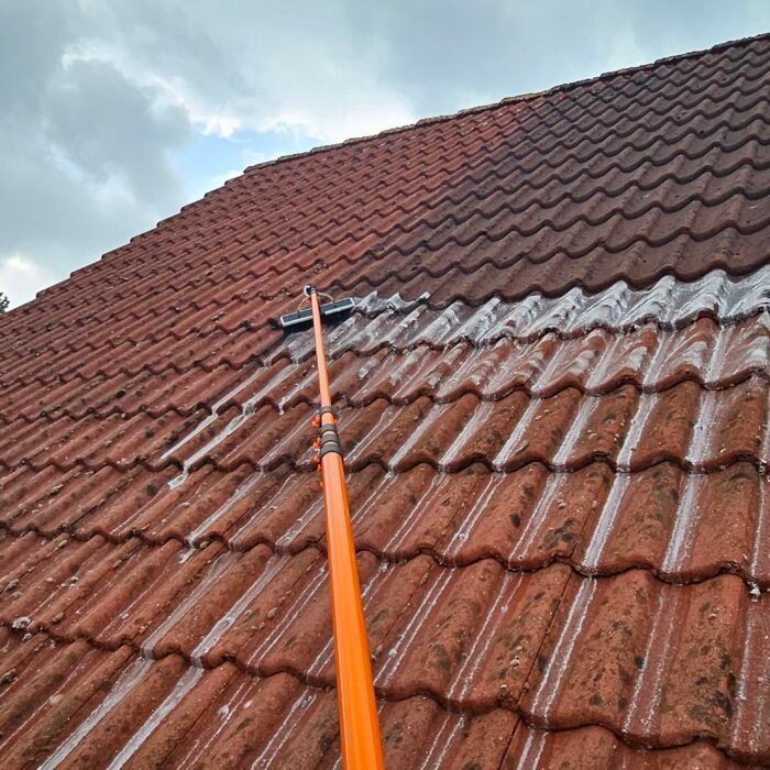 Rood pannendak met een oranje telescoopsteel op de pannen; het bovenste deel is al bewerkt, het onderste nog niet