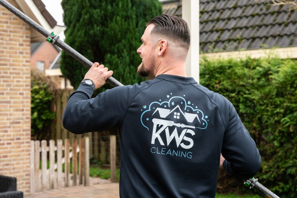 Man in een KWS-trui met een lange steel in een tuin